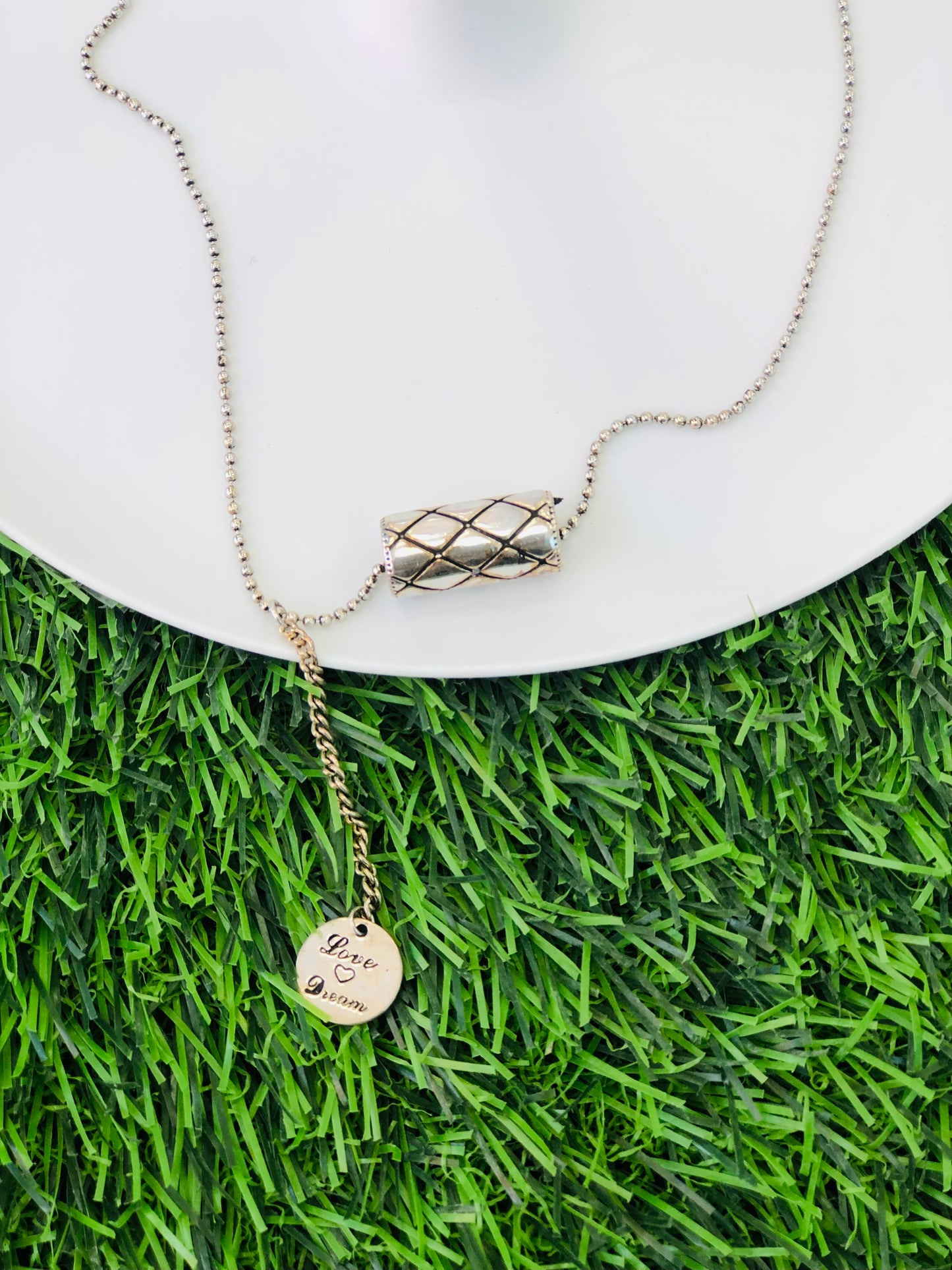 A long silver cylinder necklace and a medallion