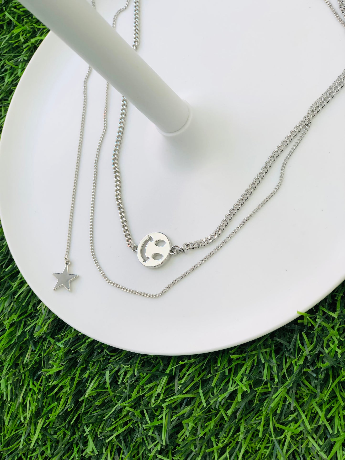 A silver necklace with two layers, a smile and a star