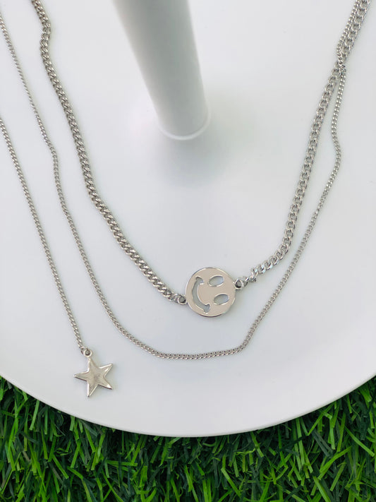 A silver necklace with two layers, a smile and a star