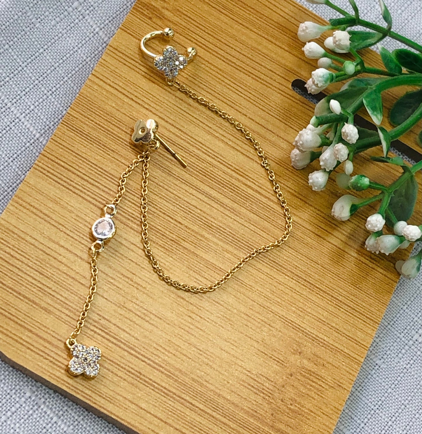 Long gold earrings wrapped around a rose