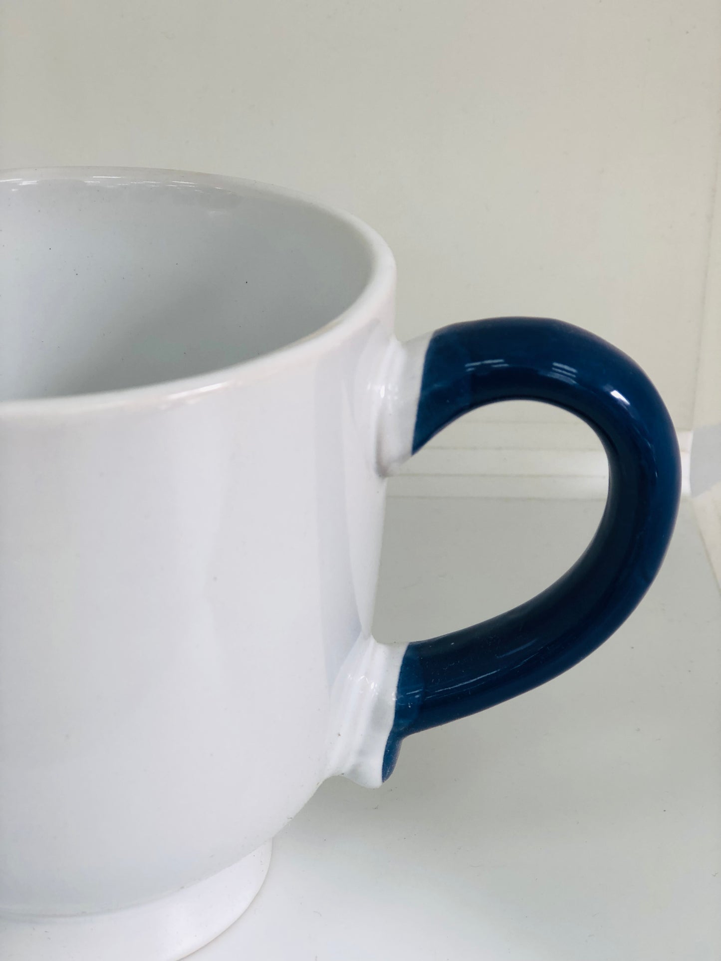 White ceramic mug with navy blue handle